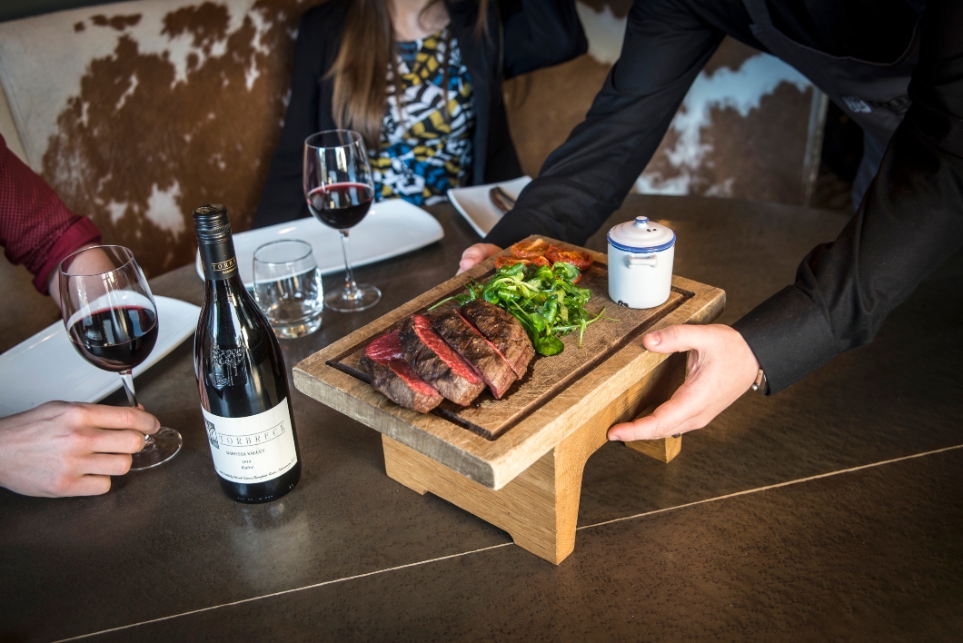 Chateaubriand steak platter and red wine being served. 