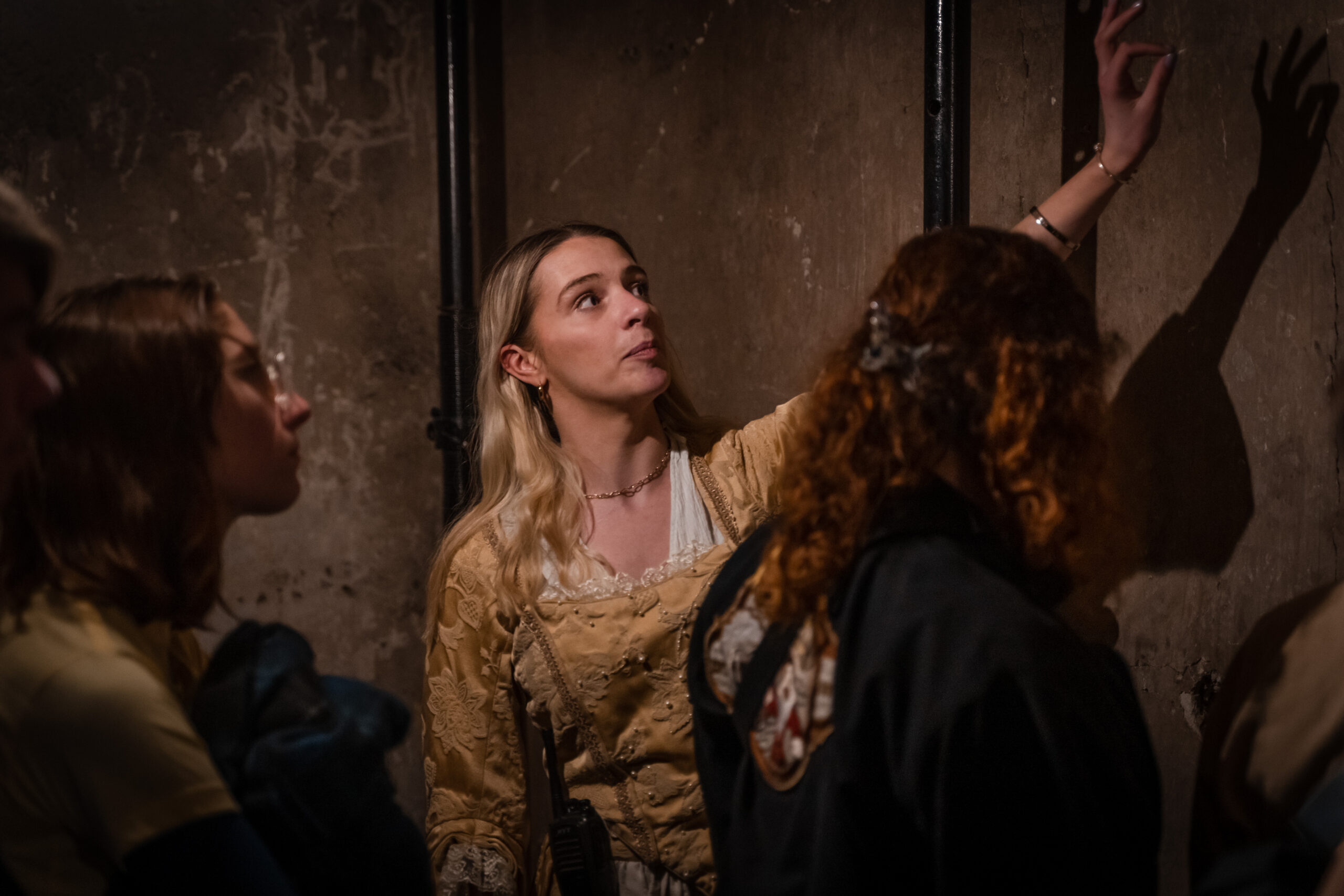 Woman with blonde hair and historical dress speaking to guests at mary king's close 